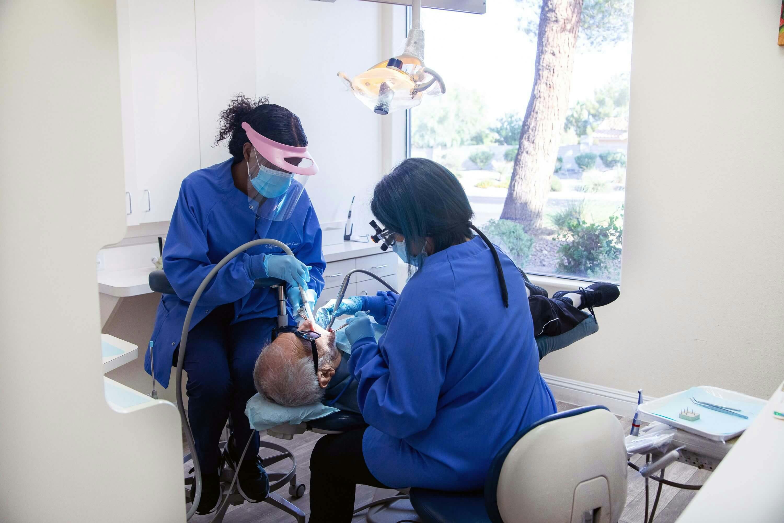 Two dental assistance in a process of a cleaning procedure for a patient